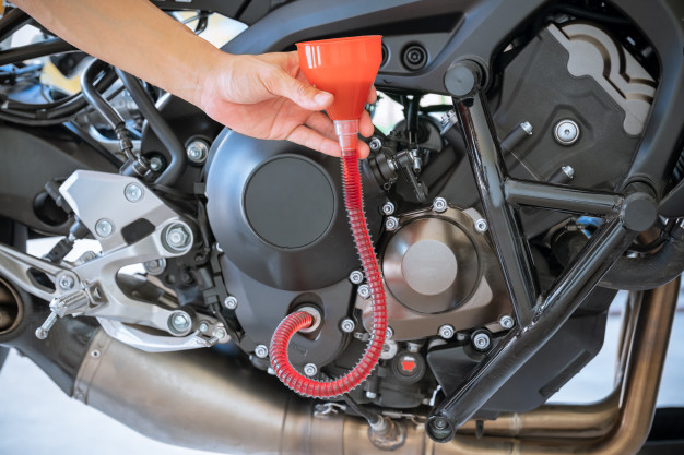 mecanico-vertido-aceite-fresco-que-vertiendo-cambio-aceite-motor-motocicleta_77569-141